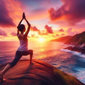 Yoga silhouette of woman on cliff with ocean and colorful sunset behind.